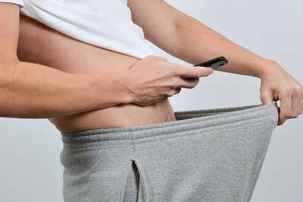 一个男人低头看着放大的阴茎